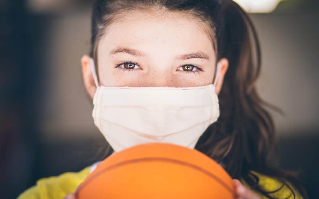 Young girl with Covid mask holding a basketball