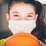 Young girl with Covid mask holding a basketball